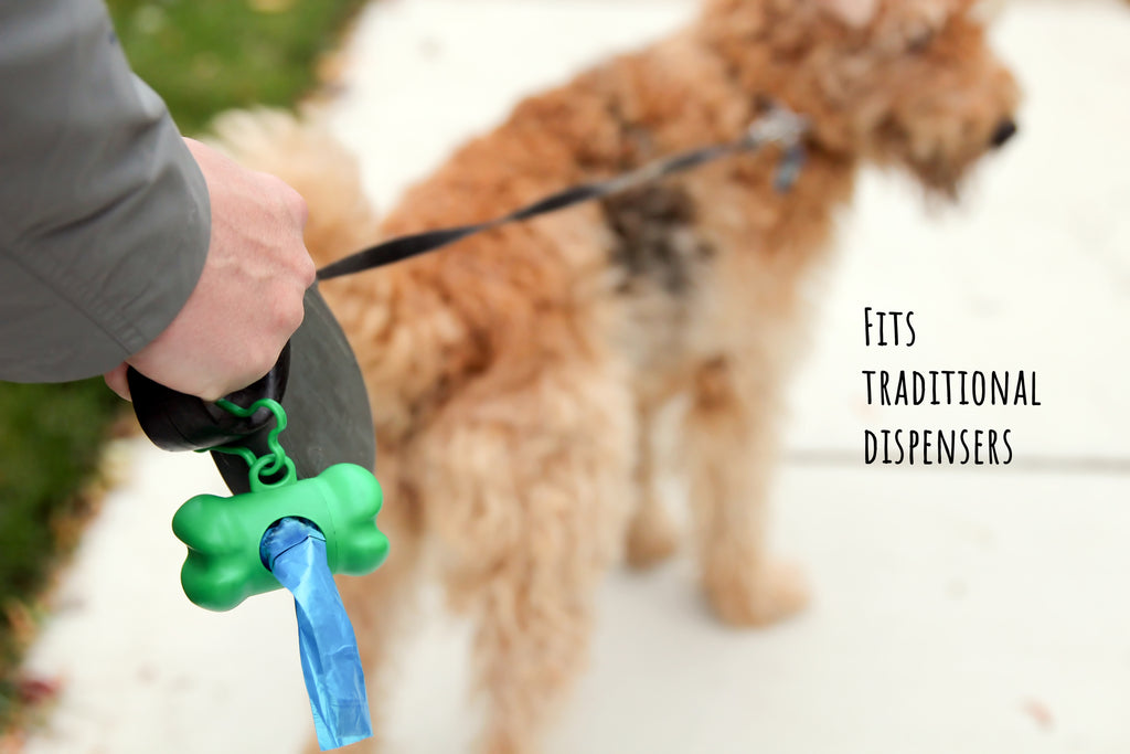 Dog being walked with a green poop bag dispenser filled will Baboo's Bags attached to a leash.