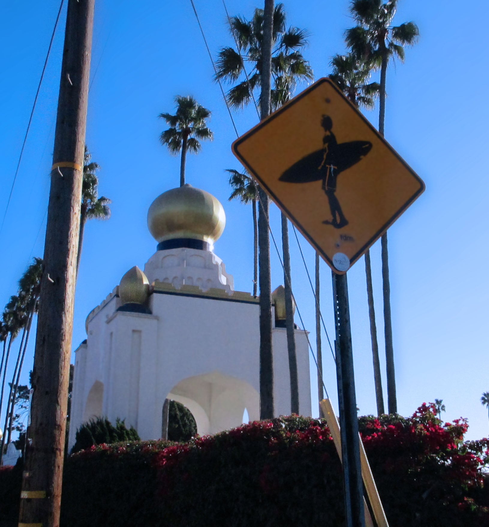 Encinitas Swami;s Surfer crossing street sign with palm trees and gold dome in the background.
